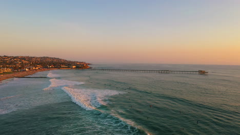 San-Diego-surfers-paradise-with-iconic-Ocean-Beach-pier-in-distance,-aerial-drone