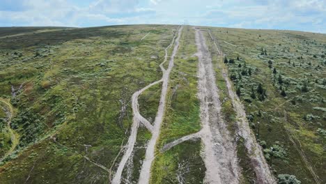 White-trail-through-the-green-landscape-of-Dalarna,-Sweden--Aerial