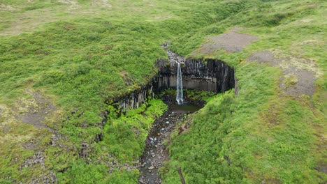 Beautiful-hidden-waterfall-of-Svartifoss,-Iceland--Aerial-pull