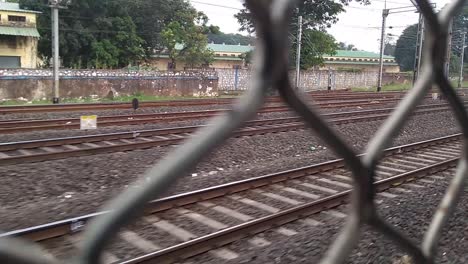 Passengers-point-of-view-from-a-window-of-an-asian-local-train,-the-criss-cross-moving-railway-tracks-and-the-trains-passing-by-give-a-feel-of-someone-travelling-in-a-train-and-looking-outside