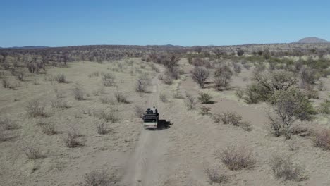 Off-Road-African-Safari-Vehicle-Dusty-Track-Aerial-Follow-Shot-Namibia