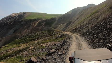 POV-over-vehicle-hood-on-narrow-off-road-trail-up-a-small-rise-and-opens-to-a-deep-valley