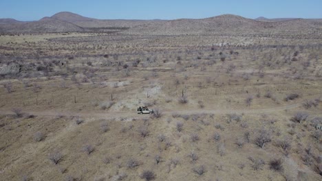Safari-Vehicle-Driving-Along-A-Mountain-Road-In-Kaokoland,-Namibia,-Africa---aerial-drone-shot