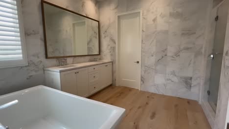 Modernes-Hauptbadezimmer-Mit-Marmorwänden-Und-Holzböden