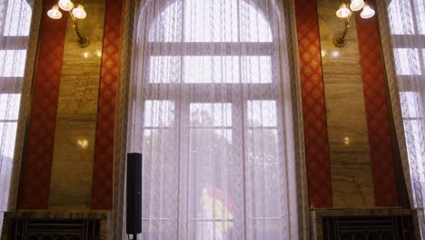 Slowly-moving-towards-big-window-framed-by-marble-wall´s-with-chandelier´s---Wedding-room