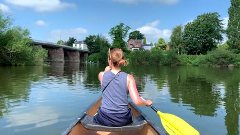 Girl-paddling-canoe-on-river-wye-on-sunny-day-with-blue-skies