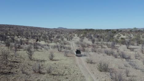 Aerial-View-African-Safari-Truck-Driving-Through-Game-Reserve,-Namibia