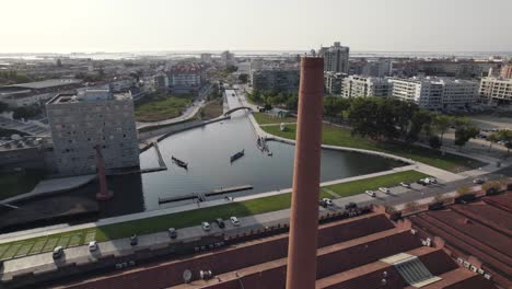 Old-factory-chimney-and-majestic-cityscape-of-Aveiro-in-Portugal,-aerial-orbit-view