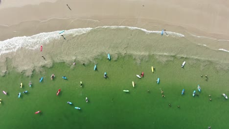 Surfers-and-colorful-surfboards-in-Hong-Kong-beach,-Aerial-view