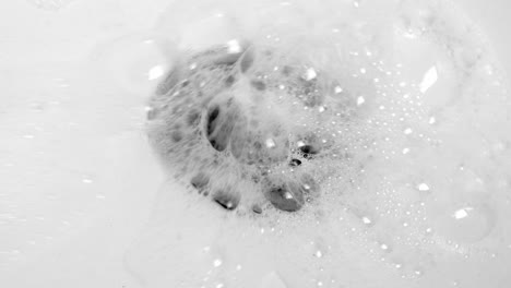 Water-Splashing-Down-In-The-Stainless-Sink-Hole-Drain-With-Lots-Of-Bubbles---high-angle,-close-up