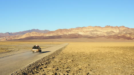 Folgen-Sie-Der-Luftaufnahme-Eines-Einzelnen-SUV-Jeeps-Auf-Der-Straße-Inmitten-Des-Heißen,-Trockenen,-Kargen-Geländes-Des-Death-Valley-Nationalparks