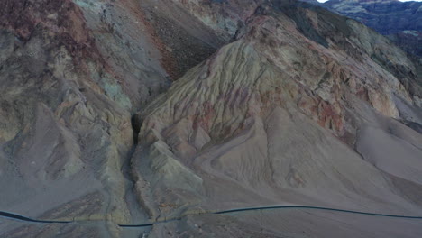 Aerial-shot-pulls-back,-reveals-cliff,-canyon-walls-along-Artist's-Drive-in-Death-Valley,-California