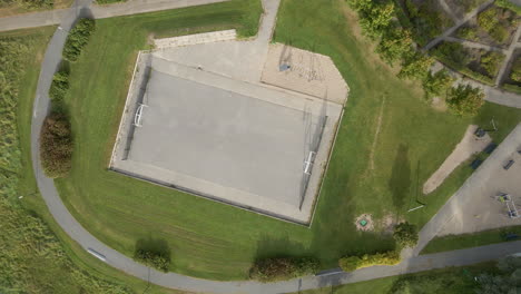 Top-down-view-of-concrete-soccer-court-on-a-playground-in-a-suburban-neighborhood---drone-lifting-up-and-spinning