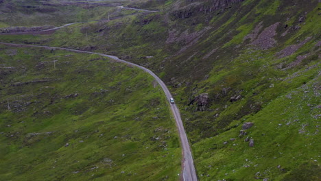 Drone-shot-following-a-van-on-Bealach-Na-Ba-Applecross-road-through-the-mountains-of-the-Applecross-peninsula,-in-Wester-Ross-in-the-Scottish-Highlands