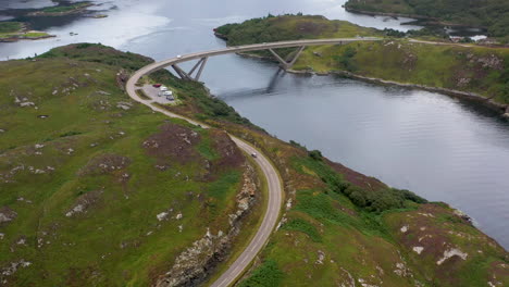 Filmische-Drohnenaufnahme-Der-Kylesku-Brücke,-Die-Einem-Auto-Folgt,-Im-Nordwesten-Schottlands,-Das-Den-Loch-A&#39;cairn-Báin-In-Sutherland-überquert