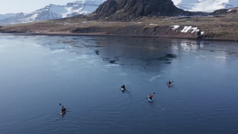 Four-kayakers-paddling-in-super-calm-fjord-water-in-Iceland,-adventure-trip