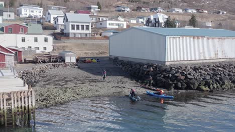 Group-of-tourist-returning-kayaks-at-rental-place-in-small-Icelandic-town,-aerial