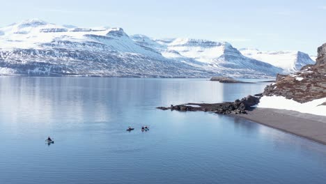 Kayakistas-De-Aventura-En-El-Impresionante-Paisaje-De-Islandia,-Montañas-Blancas-De-Fondo