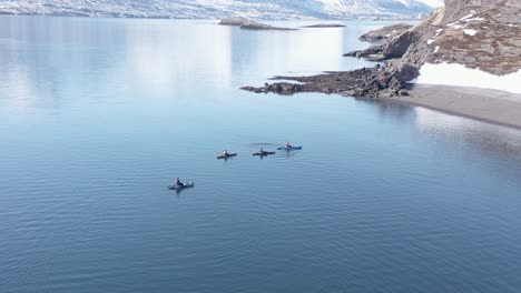 Kayakers-calmly-floating-on-waveless-water-in-serene-Reydarfjordur-fjord,-aerial