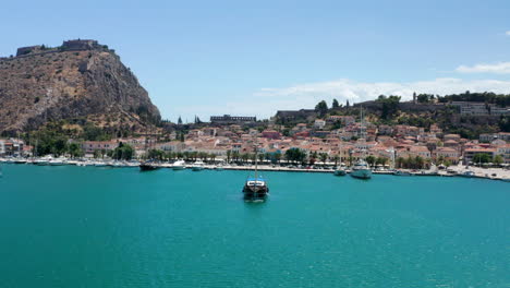 Old-Wooden-Boat-Leaving-At-Nafplio-Port-With-Fortress-of-Palamidi-In-The-Background-In-Greece