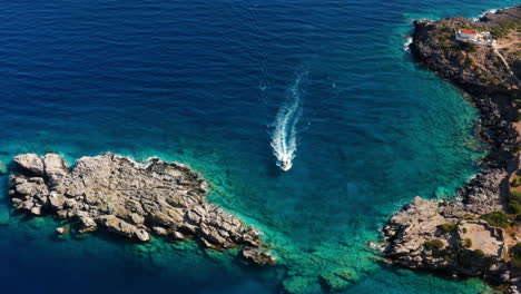 Lancha-Rápida-Navegando-En-El-Mar-Azul-Turquesa-Entre-Afloramientos-Cerca-De-Loutro-En-Creta,-Grecia