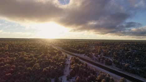 4K-aerial-over-remote-winter-forest-road-during-beautiful-colorful-sunrise