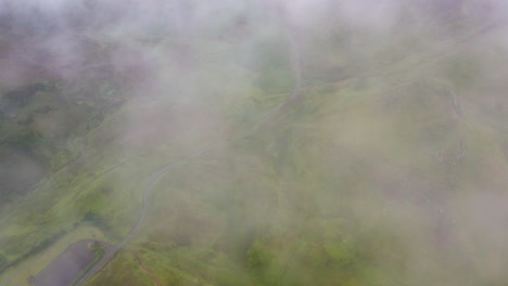 Filmische-Drohnenaufnahme-Im-Abwärtswinkel,-Die-Durch-Die-Wolken-Kommt-Und-Die-Bergseite-Von-Quiraing-In-Schottland-Zeigt