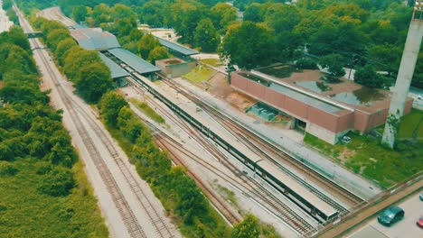 Drone-footage-of-a-train-passing-underneath-a-bridge-full-of-traffic-into-a-station