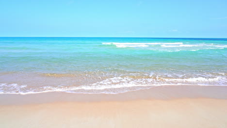 Foamy-turquoise-waves-rolling-over-white-sand-beach-in-Thailand-on-idyllic-sunny-day
