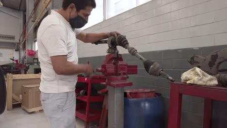 Lateinischer-Männlicher-Techniker,-Der-Die-Antriebswelle-Eines-Autos-In-Einer-Werkstattstationsgarage-In-Mexiko-Lateinamerika-Repariert