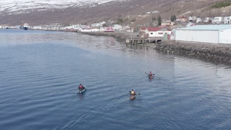 Kayakers-arriving-back-at-fishing-town-Eskifjördur-in-East-Iceland,-aerial