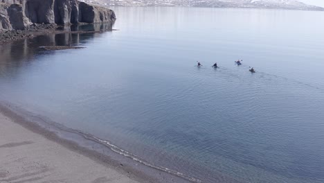 Kayakers-paddling-in-calm-water-of-Eskifjörður-in-Iceland,-moving-away-from-shore