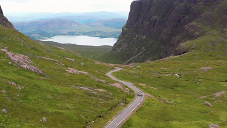 Drone-shot-of-van-on-Bealach-Na-Ba-Applecross-road-through-the-mountains-of-the-Applecross-peninsula,-in-Wester-Ross-in-the-Scottish-Highlands