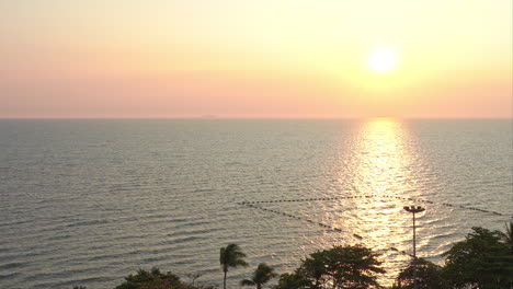 Rosa-Bunter-Sonnenuntergang-Am-Meer-Mit-Sonnenlicht,-Das-Sich-In-Der-Wasseroberfläche-Widerspiegelt,-Palmen-Im-Vordergrund,-Thailand