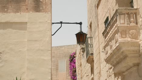 Lamp-On-Wall-Of-Building-Along-Medieval-Street-On-A-Sunny-Day
