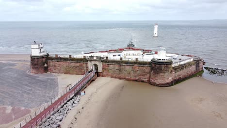 Fort-Perch-Rock-New-Brighton-sandstone-coastal-defence-battery-museum-aerial-rising-view-with-lighthouse