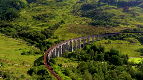 Rotating-drone-shot-of-famous-railroad-bridge-in-the-Glenfinnan-Viaduct-with-train-on-the-tracks