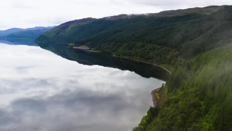 Drone-shot-starting-in-the-clouds-flying-towards-mountains-and-shore-in-Loch-Carron,-in-the-Scottish-Highlands
