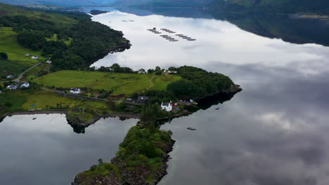 Wide-Rotating-drone-shot-of-reflecting-water-at-Loch-Carron,-in-the-Scottish-Highlands