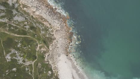 Aerial-shot-of-a-drone-flying-high,-over-the-beach-of-Church-Ope,-and-following-the-coast-line-on-the-island-of-Portland,-Dorset-UK