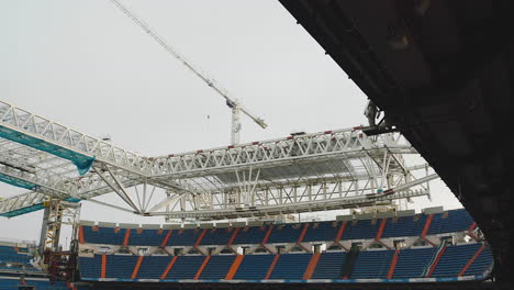Steel-Roof-Trusses-And-Tower-Crane-Over-Bleachers-At-Stadium-Construction-Site