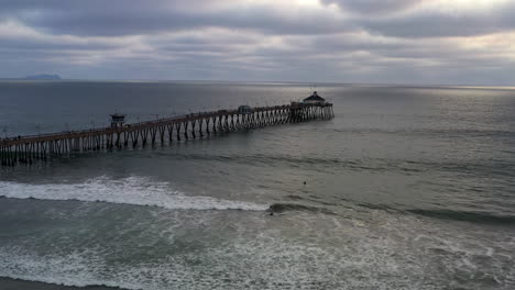 Surfers-Swimming-At-Imperial-Beach-Pier-In-San-Diego-On-A-Cloudy-Sunset
