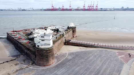 Fort-Perch-Rock-New-Brighton-sandstone-coastal-defence-battery-museum-Peel-port-cranes-aerial-view-dolly-forward-left