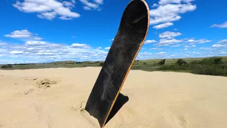 A-skateboard-deck-without-wheels-sticking-out-of-the-sand-in-a-desert-on-a-hot-sunny-day