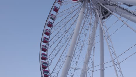 Shot-of-the-side-of-a-ferry-wheel-with-red-capsules-during-the-day-with-a-clear-blue-sky