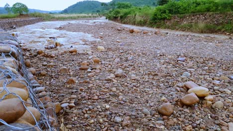 Household-garbage-flowing-with-rainy-water-in-rocky-creek-during-rainy-season