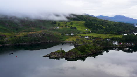 Cinematic-revealing-drone-shot-of-Loch-Carron-with-low-lying-clouds-covering-the-mountains,-in-the-Scottish-Highlands