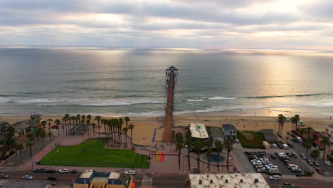 Aerial-View-of-People-Leisurely-Strolling-At-Imperial-Beach-With-Pier-Spanning-Over-Pacific-Ocean-At-Dusk