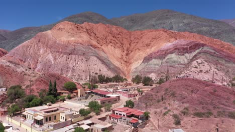 Drone-flying-forwards-revealing-a-village-at-the-foot-of-the-Hills-of-Seven-Colors-in-Jujuy-Province,-Argentina