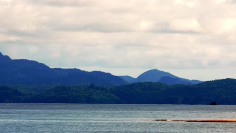 View-of-the-seaside-overlooking-the-sea-and-mountains-with-gentle-waves-on-a-holiday-in-good-weather,-Satun-Province,-Thailand